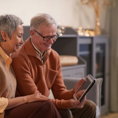 Elderly Parents sitting on sofa looking at tablet