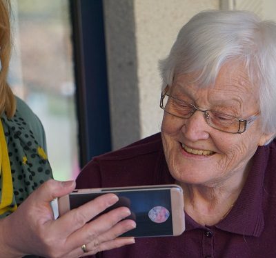 Carer holding phone for elderly woman