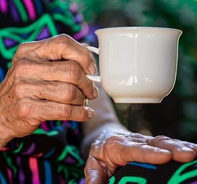 an elderly person drinking tea at home