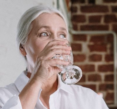 elderly woman drinking water to avoid dehydration